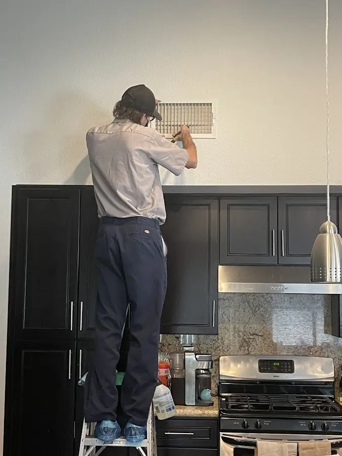 Technician inspecting an air vent during HVAC service in Moss Point